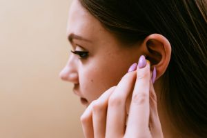 A woman puts earplugs in her ears.