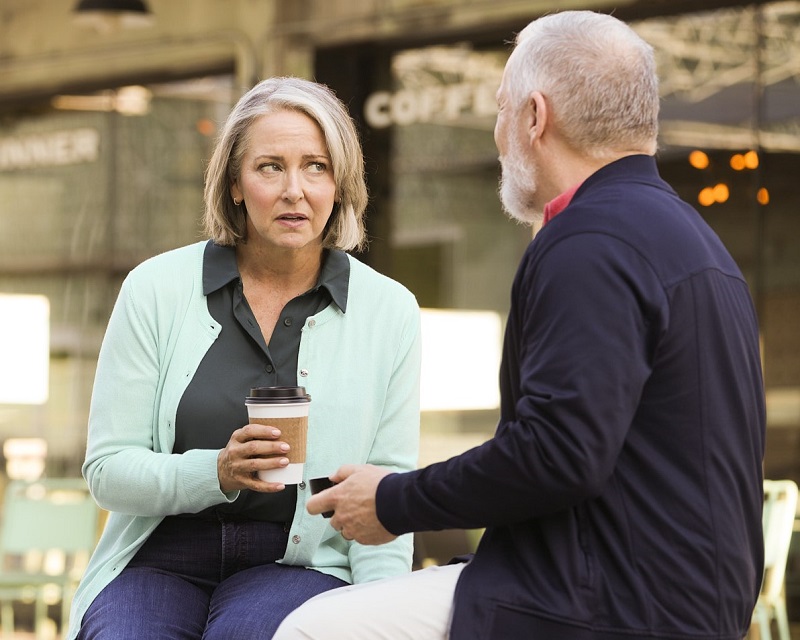 A woman struggles to hear a man talking.