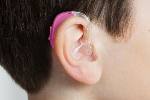 close-up on bright pink pediatric hearing aid on a child's ear