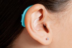 close-up on bright blue pediatric hearing aid on a child's ear