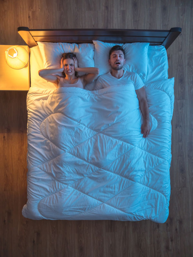 A woman indicates frustration at her snoring bed partner.