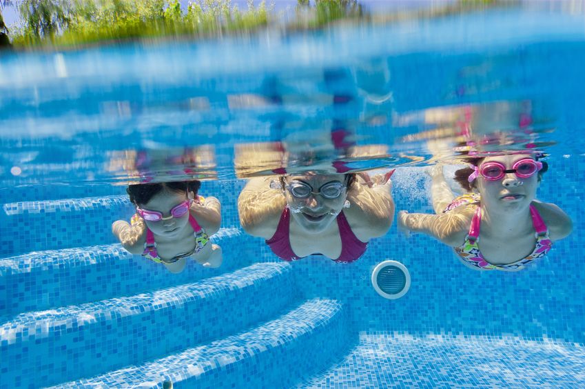 Kids swimming underwater in a pool.