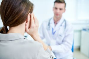 A woman at a doctor's office, discussing tinnitus.