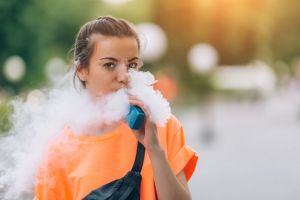 A girl uses a vape pen.