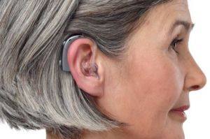 A woman wears a hearing aid with an earmold.