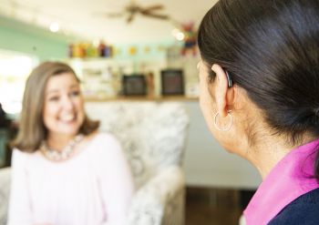 A woman with a hearing aid talks to a friend.
