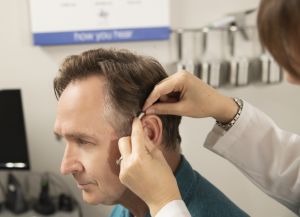 A man tries on a hearing aid.