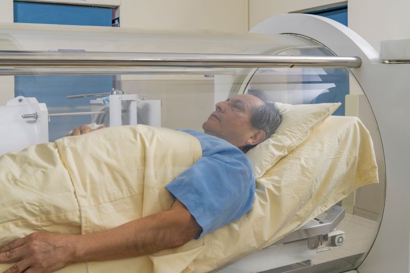 A man sits in a hyperbaric oxygen therapy chamber. 