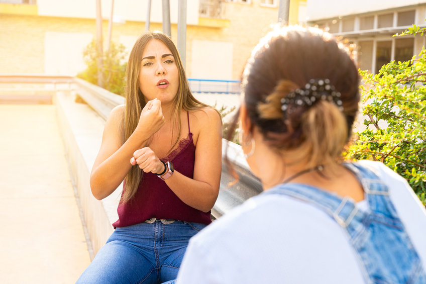 A woman uses American Sign Language to chat with a friend. 