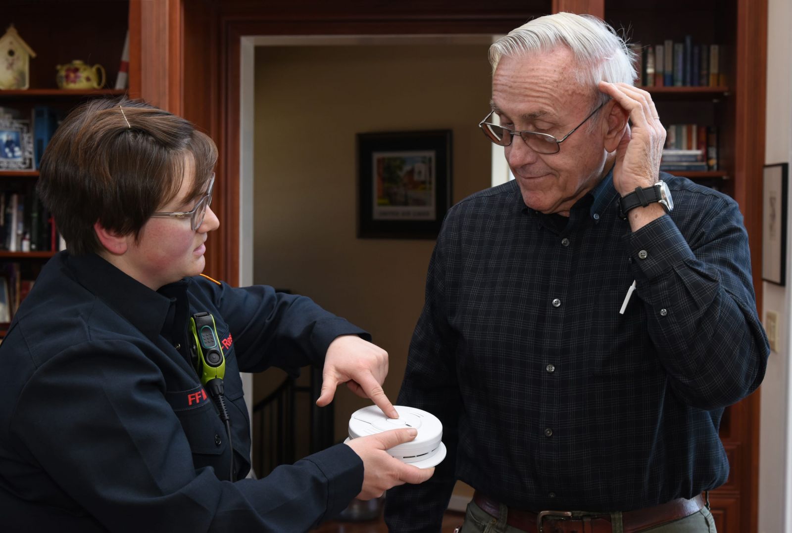 A fire safety technician tests the sound levels with an older adult who has hearing loss. 