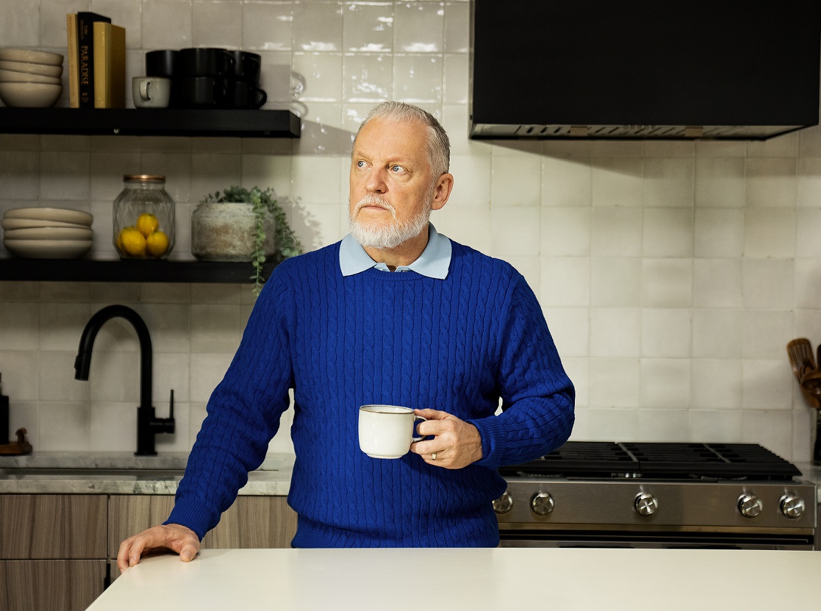 A man holding a cup of coffee and staring into space